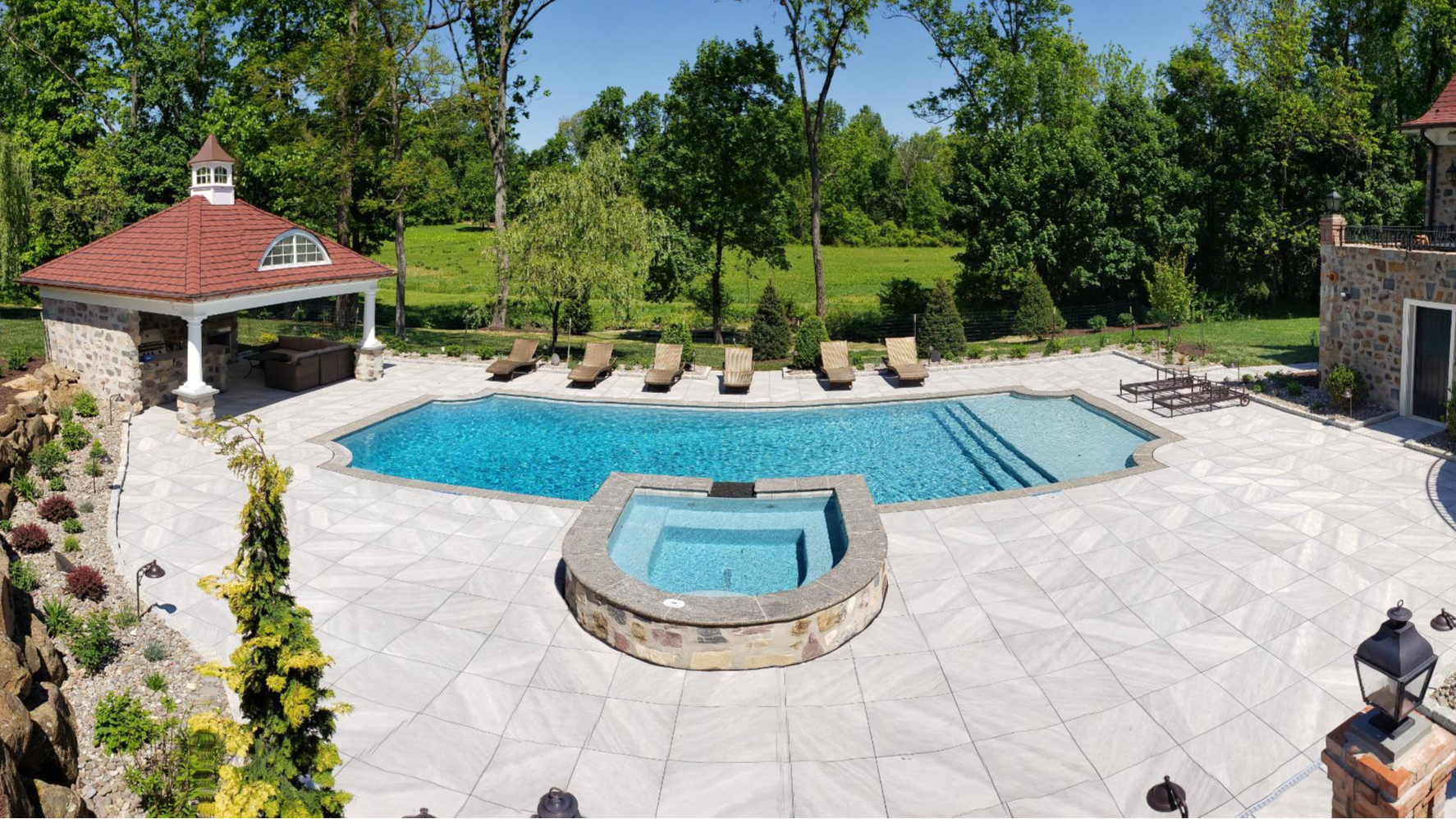 Backyard oasis with swimming pool, spa, pool house, covered outdoor kitchen, and other hardscaped outdoor entertaining area in Easttown Township, Chester County, PA. Alta provided Civil Engineering & Land Development, Structural Engineering, Land Survey, and Plumbing Design services for this project. Concept and construction by Armond Aquatech Pools, Inc.